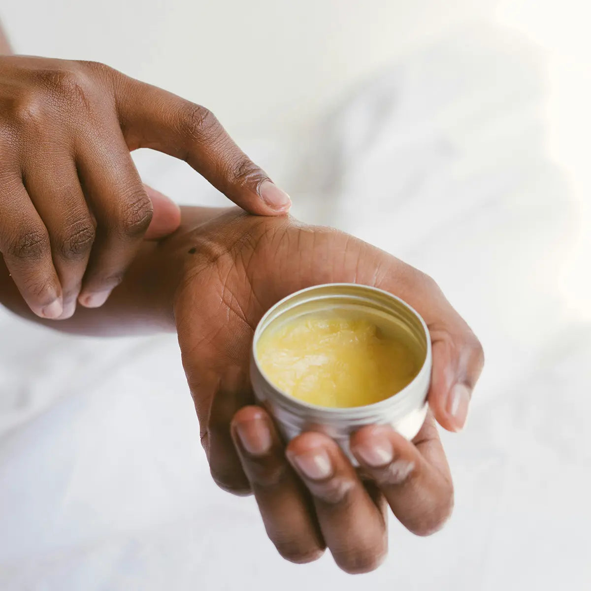 des mains qui tiennent une crème hydratante